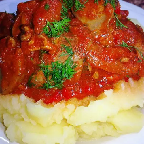 a plate with tomato onion chicken livers and mashed potatoes