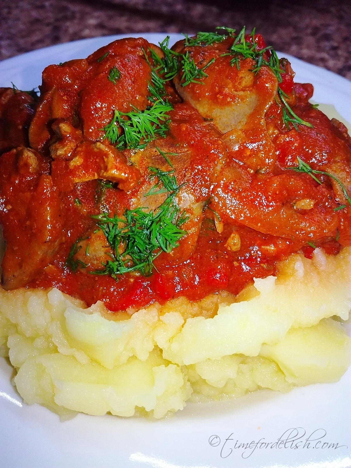 a plate with tomato onion chicken livers and mashed potatoes